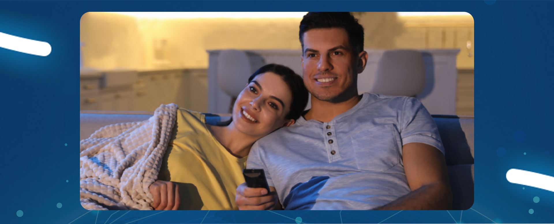 młoda para ogląda TV leżąc w łóżku pod kocem