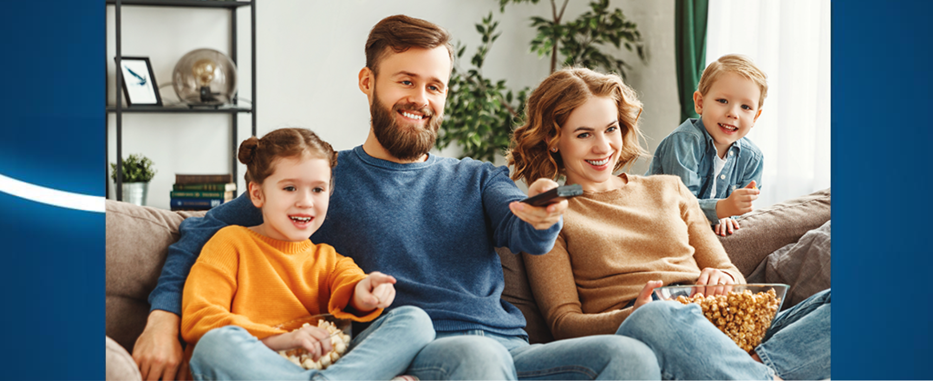 para z dwójką dzieci siedzą na kanapie, mężczyna trzyma pilot w ręce