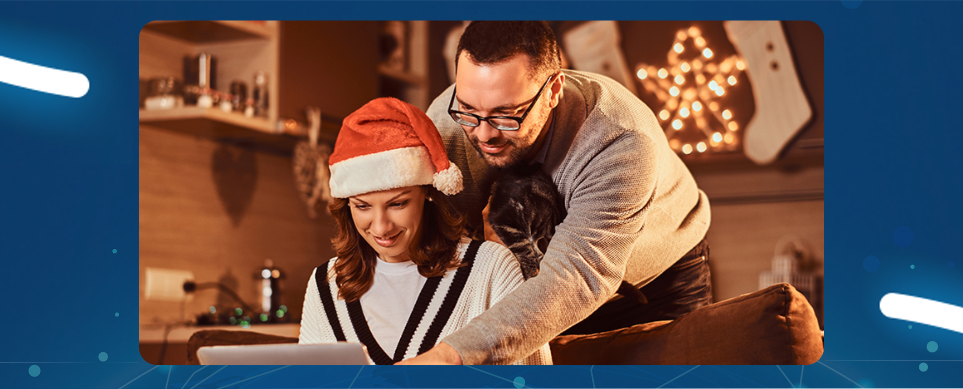 kobieta w czapce mikołaja patrzy na ekran laptopa a mężczyzna stoi obok i pokazuje coś na laptopie