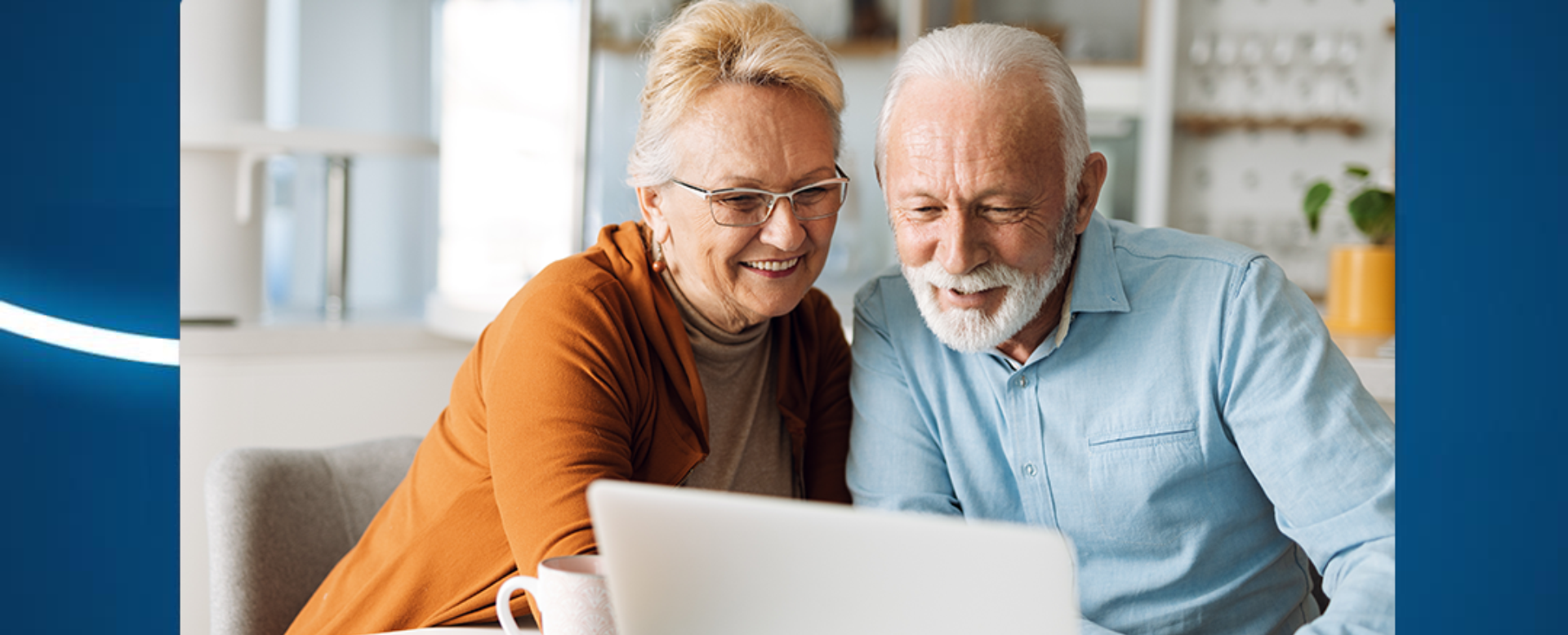 starsza para uśmiecha się oglądając coś na laptopie